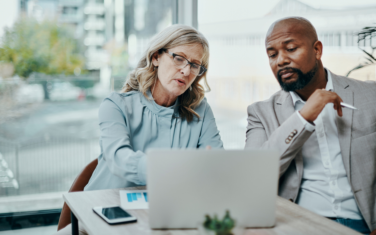 Shot of a businessman and businesswoman using a laptop together in a modern office